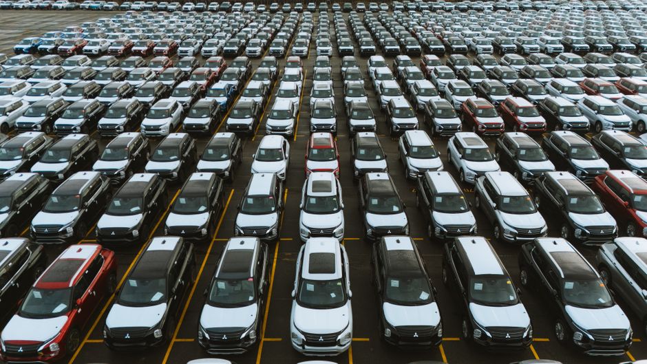 Row of new cars lined up on a UK dealership forecourt at dawn